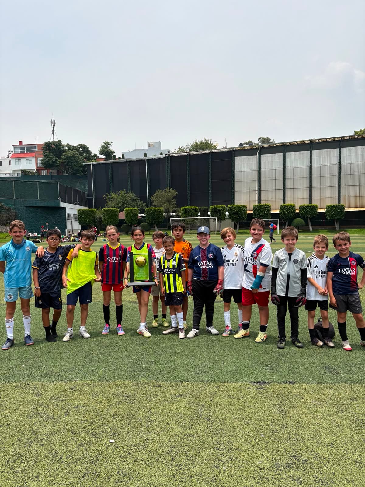 Niños y niñas del Curso de Verano Falcons posando en fila con el balón dorado