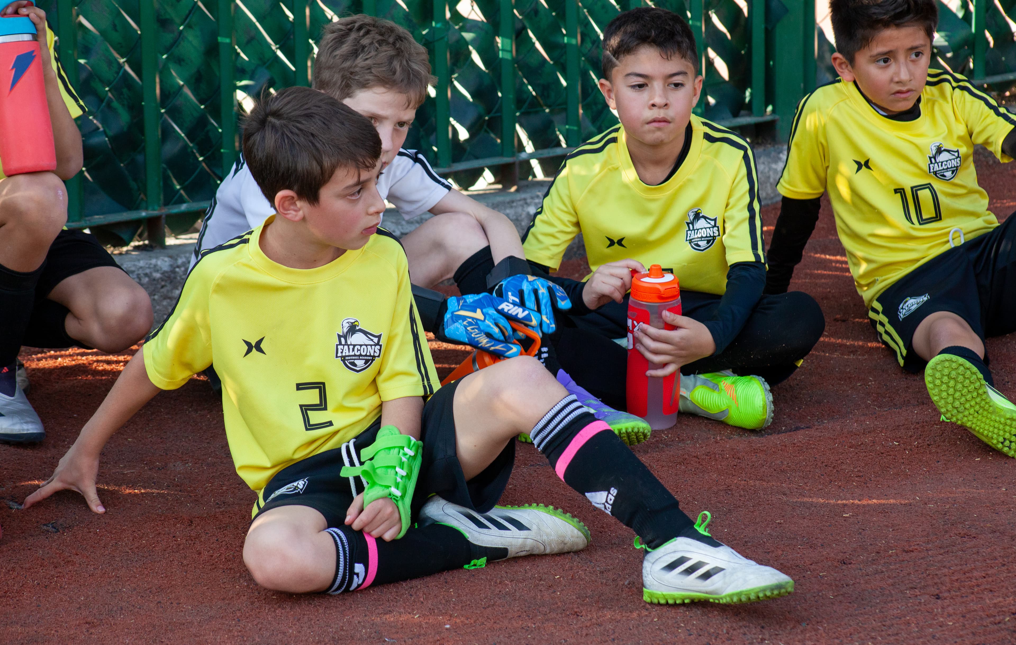 Dos jugadores Falcons con uniforme amarillo descansando con sus guantes y termo