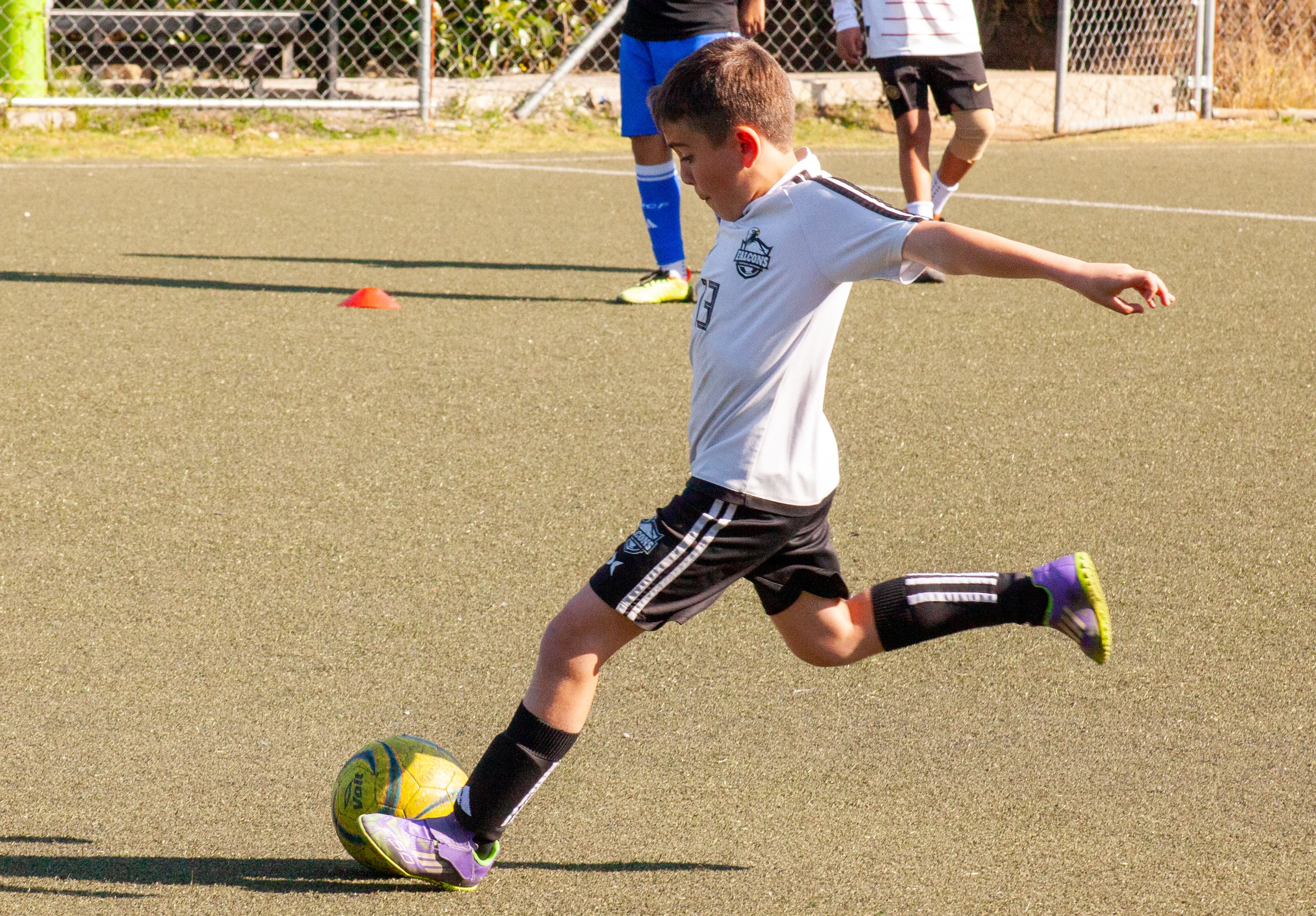 Jugador Falcons en uniforme blanco pateando el balón durante entrenamiento