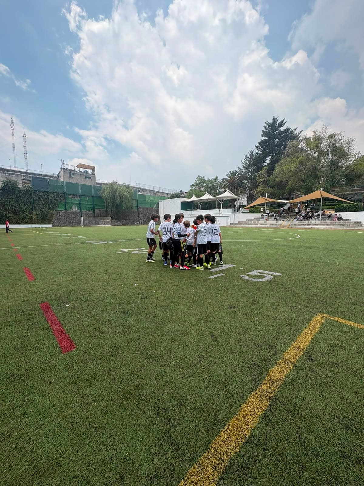 Equipo del Curso de Verano Falcons FA en plática técnica en la cancha del Colegio Merici